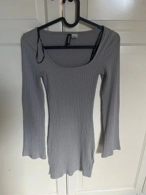 Grå ribbad långärmad klänning Gina Tricot - Säljer en grå, ribbad kortklänning från h&m. Klänningen har lång ärm, rundad urringning och är figurnära i modellen. Perfekt för dig som gillar enkel men snygg stil.