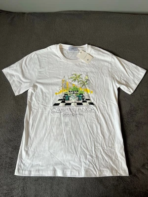 Vit Casablanca Grand Prix T-shirt - Exklusiv t-shirt från Casablanca med det populära Grand Prix-trycket på bröstet. Helt ny och oanvänd med originaltaggar kvar.  • Storlek: M • Färg: Vit • Material: 100 % bomull • Skick: Ny med lappar  Ett stilrent premiumplagg som passar perfekt till sommaren.  📦 Skickas snabbt och spårbart.