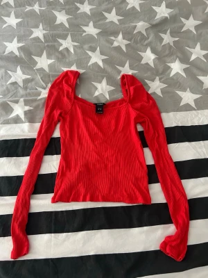 Röd ribbad långärmad topp  - Trendig röd topp från lindex med ribbad struktur och långärmade puffärmar. Fyrkantig ringning ger en snygg och modern look. Perfekt för att lyfta din outfit med en färgstark detalj. Använd ett fåtal gånger 