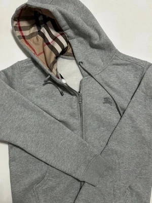 Burrberry Zip Up - Säljer en snygg Burberry Zip Hoodie i nästan ny skick 9.5/10✅Tröjan är storlek L men passar M✅Lapparna medföljer ej pga tappat bort dem🤗Hör av er vid frågor och funderingar🤩🤝