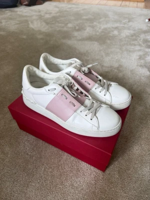 Valentino Garavani skor  - Snygga vita och rosa sneakers från Valentino🩷 Nyrpis är 5 425kr. De är i bra skick och har bara använts några få gånger, men det finns små skavningar där fram som syns på bilderna. Kvitto, dustbag, äkthetsbevis och kartong finns! 