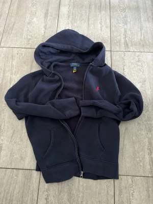 Hoodie med dragkedja från polo Ralph lauren storlek L 14-16 år i mycket bra skick - Använd ett fåtal gånger och i ett mycket bra skick.Nypris 1200 kr