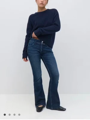 Mörkblå mid waist  bootcut jeans - Snygga mörkblå bootcut jeans med klassisk femficksmodell och kontrastsömmar. Jeansen har en något utsvängd passform från knät och ner, vilket ger en retrovibe. Tillverkade i denim med stretch för extra komfort.