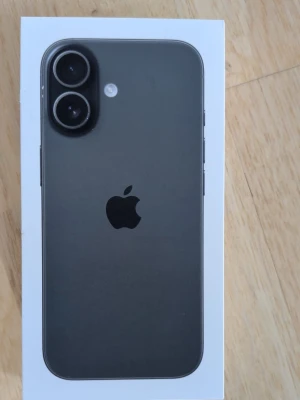 iPhone 17 svart 256GB från Apple - Snygg svart iPhone 17 med 256GB lagring. Telefonen har en stilren design i glas och aluminium, med en stor kamera på baksidan och den klassiska Apple-loggan. Perfekt för dig som vill ha en kraftfull och modern smartphone.