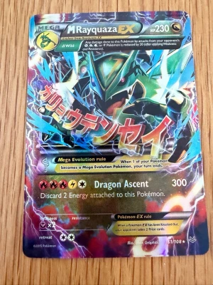 Pokémonkort Mega Rayquaza EX - Säljer ett samlarkort från Pokémon, Mega Rayquaza EX med holografisk yta och japansk text. Kortet har färgstark design med Rayquaza i centrum och detaljer i blått, grönt och guld. Perfekt för dig som gillar Pokémon och vill utöka din samling.