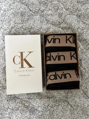 kalsonger 3-pack - kalsonger i 3-pack med bred beige resår och svart logga. Kalsongerna är svarta och har en klassisk boxermodell. Perfekta för dig som gillar stilrena och bekväma underkläder från ett välkänt märke.