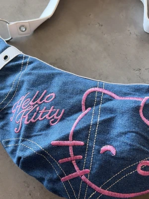 Bershka Hello Kitty Mania Bag  - Säljer en söt axelväska i blå denim med broderad Hello Kitty-design i rosa ifrån märket bershka.  💕