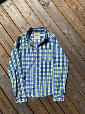 Hollister skjorta ~ Vintage  - Säljer denna skjorta från Hollister. Storlek M. Passar perfekt för dig som är mellan 175-180! Hör av er vid frågor eller minsta fundering 🙌  Märke: Hollister  Storlek: M  Färg: Ljusgrön, blå och vit/rutig  Skick: Mycket bra utan defekter   Se mått nedan:  Längd: 66,5 cm  Bred: 48,5 cm  Ärm: 67 cm