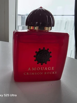 Amouage Crimson Rocks parfym 100ml - Lyxig parfym från Amouage, modellen Crimson Rocks. Flaskan är djup röd med gulddetaljer och har en elegant, kupolformad kork. Volymen är 100 ml. Flaskan har en exklusiv och modern design som verkligen sticker ut på parfymhyllan.