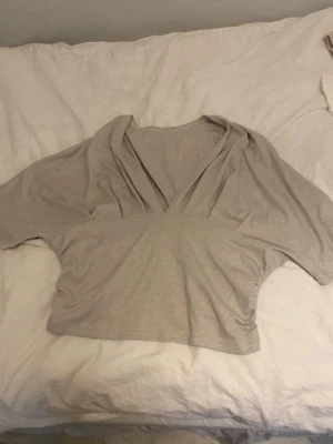 Beige croppad omlottopp - Aldrig använda men har ett pyttelitet hål i sömnen på sidan där av låga priset