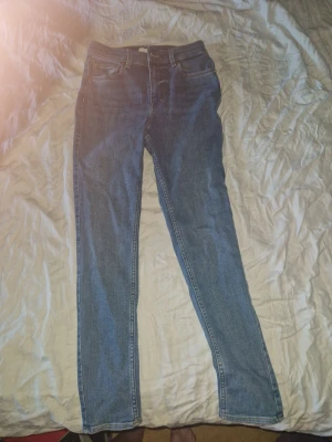 Blå skinny jeans från H&M - Snygga blå skinny jeans från H&M i klassisk femficksmodell. Jeansen har hög midja och smala ben. Storlek : 38 Nypris : 299. Bara provade, de var för små. 