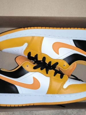 Nike Air Jordan 1 Low black taxi - Snygga Nike Air Jordan 1 Low sneakers i gult, svart och vitt med orange swoosh. Skorna har klassisk låg siluett, svart snörning och vit sula. Ovandelen är i läder och designen är riktigt clean och sportig, perfekt för dig som vill sticka ut med färg. Använt ett fåtal gånger. Om ni har några frågor så är det bara att fråga. Priset är inte hugget i sten och det blir även billigare om det är snabb affär 