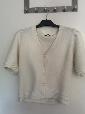 Vit stickad tröja från  Gina Tricot - Vit stickad kort ärmad tröja från Gina Tricot med knappar 