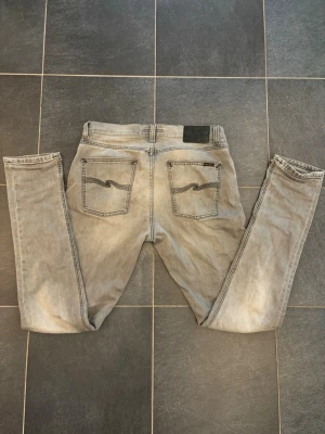 Grå jeans från Nudie - Säljer ett par gråa jeans från Nudie med en riktig snygg tvätt. Bra skick och riktig najs jeans nu till sommaren. L34 W31. Hör av er vid frågor.