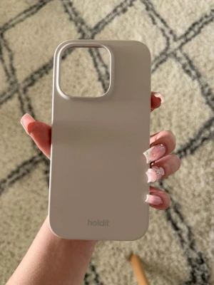 Beige mobilskal från Holdit - Snyggt och stilrent beige mobilskal från Holdit. Skalets design är minimalistisk med en matt finish och rundade hörn. Tillverkat i mjukt silikonmaterial som ger ett bra grepp och skyddar mobilen mot repor. Perfekt för dig som vill ha ett enkelt men trendigt skal. iPhone 14 Pro 