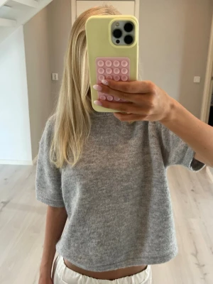 Grå stickad kortärmad topp - Mjuk och enkel grå stickad tröja med korta ärmar och rund hals. Tröjan har en avslappnad passform och är perfekt för lager på lager. Materialet är skönt och mysigt. Perfekt till sena sommarkvällar eller till en dag mitt i hösten. 💞💞