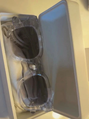  Solglasögon från CHIMI - Snygga solglasögon från CHIMI med grå/ transparent båge och mörka glas. Rektangulär form som ger en modern vibe. Kommer i originalfodral med putsduk. Perfekta för dig som vill sticka ut med stilrena accessoarer.