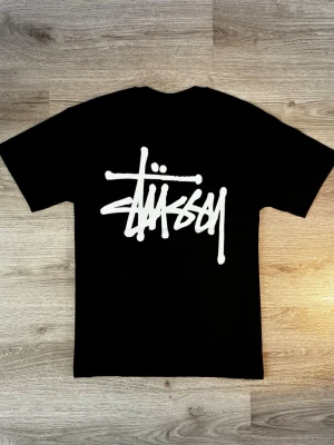 Stüssy / stussy t-shirt - Svart, Strl. M - sparsamt skick, inga slitage - Svart t-shirt från Stüssy med stor vit logga på ryggen och mindre logga på bröstet. Klassisk passform med rund hals och korta ärmar. Perfekt för dig som gillar streetwear och vill sticka ut med en ikonisk look.