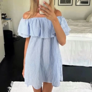 Blåvit offshoulder kortklänning - Söt blåvit randig kortklänning med offshoulder-design och volang upptill. Klänningen har en luftig passform och är perfekt för varma dagar. Tillverkad i ett lätt bomullsmaterial som känns skönt mot huden. Från Zara storlek M men passar mer S💓