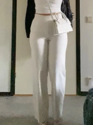 Vita linnebyxor med hög midja - Säljer ett par stilrena vita linnebyxor med hög midja och raka ben. Byxorna har en enkel design utan synliga detaljer och är perfekta för en clean och fräsch look. Materialet är lätt och luftigt, vilket gör dem sköna att bära under varma dagar.