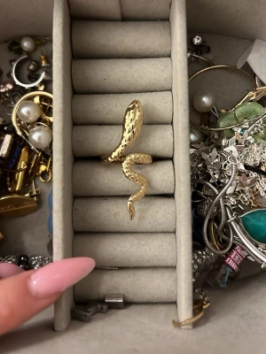 Guldfärgad ormring i metall - Cool ring i form av en orm, tillverkad i guldfärgad metall med detaljerad yta som ger ett lyxigt intryck. Ringen slingrar sig runt fingret och har en unik, trendig design som sticker ut.