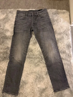 Grå slim fit jeans - Snygga grå slim fit jeans med klassisk femficksdesign och diskreta slitningar framtill. Jeansen har raka ben och normal midja, perfekta till en avslappnad stil. Materialet är mjukt denim i bomull med lite stretch för extra komfort.