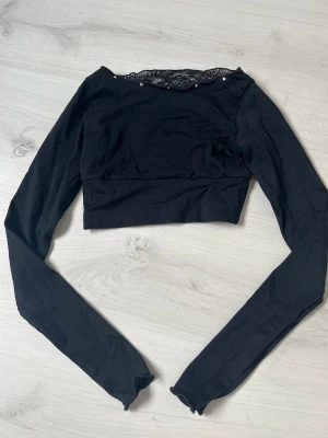 Träningstopp - Kroppad svart träningströja i lång ärm och spets från Karisma. Passar bra till konståkning. Lappen med storlek är bortklippt, skulle säga omkring 134/140. Ordinarie pris är 1200 kr 🩷