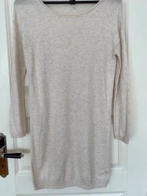 Cremefärgad stickad kort klänning med 3/4-ärm - Cremefärgad stickad kort klänning från H&M med rund halsringning och 3/4-långa ärmar. Klänningen har en rak passform och ribbade muddar vid ärmslut och nederkant. Perfekt basplagg till våren.