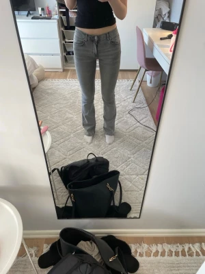 Grå raka jeans med hög midja - Säljer ett par grå jeans med rak passform och hög midja. Jeansen har klassisk femficksdesign och stängs med knapp och dragkedja. Perfekta för en avslappnad och trendig look. Materialet känns mjukt och stretchigt för extra komfort. (Jag är 175)