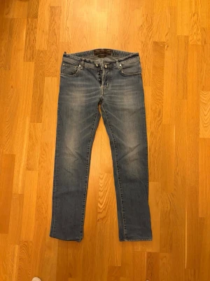 Jacob Cohen jeans without patch  - Säljer ett par klassiska blå Jacob Cohen jeans med raka ben och lätt slitna detaljer framtill. Jeansen har fem fickor, normal midja och dragkedja med knapp. Perfekta för en avslappnad och stilren look. Materialet är denim i bomull.