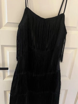 Fransklänning - Svart klänning med smala axelband och flera lager med fransar