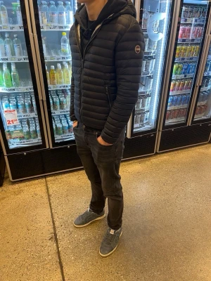 Colmar jacka - Säljer en svart pufferjacka med huva och dragkedja framtill. Jackan har diskreta horisontella sömmar och en patch på ärmen. Perfekt för kalla dagar och har en modern, slimmad passform. Passar dig som vill ha en stilren och enkel vinterjacka. Pris kan diskuteras!