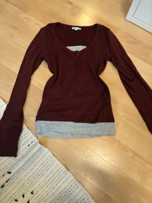 Vinröd långärmad henley  - Vinröd långärmad henley topp från subdued med rund halsringning och tre knappar framtill. Toppen har en grå kant nedtill som ger en lager-på-lager-look. Tillverkad i mjuk bomull. Använd en gång så den är som ny! Storlek s men passar även xs! Y2k stil! Buda gärna!!