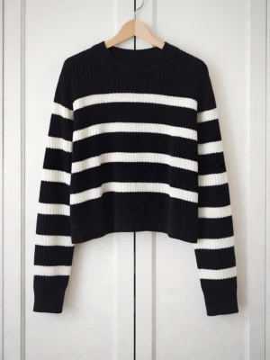 Svartvit randig stickad tröja - Trendig stickad tröja med breda svarta och vita ränder. Modellen har rund halsringning, långa ärmar och ribbstickade muddar. Croppad passform som ger en modern look. Perfekt för dig som gillar klassiska färgkombinationer och stilrena plagg.