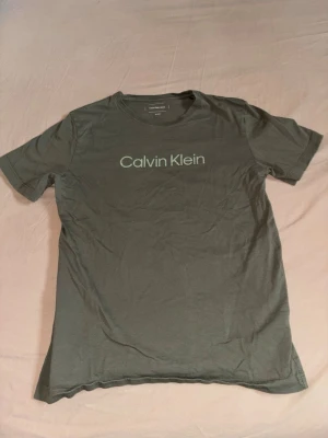 Grön Calvin Klein t-shirt - Snygg grön t-shirt från Calvin Klein Jeans med klassisk logga tryckt över bröstet. T-shirten har rund halsringning och korta ärmar. Tillverkad i mjuk bomull för skön känsla och enkel stil.