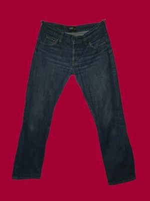 Lee jeans - Snygga mörkblå jeans från Lee med klassisk femficksdesign och raka ben. Jeansen har subtila slitningar och kontrastsömmar, samt en Lee-lapp bak i midjan. Tillverkade i slitstark denim som ger en tidlös look.
