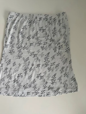 Vit H&M tubtopp med blixtar, storlek 40 - Gullig vit tubtopp / topp / linne från H&M Divided i storlek 40. Stabil reså i toppen som håller allt på plats och följsamt stretchigt tyg med svarta blixt-mönster. Multifunktionell, går även att använda som kjol. Mycket fint skick, som ny!  (Skickas helst, men kan även hämtas i Stockholm vid behov)