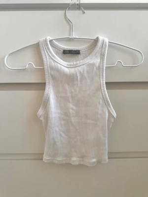 Vit ribbad linnetopp från Zara - Säljer en enkel och fräsch vit ribbad linnetopp från Zara. Toppen är croppad och ärmlös med rund halsringning, perfekt för varma dagar eller som lager under en skjorta ☀️🫶🏻 Materialet är mjukt och stretchigt för en bekväm passform