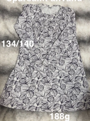 Vit nattlinne med svart bladmönster - Mysigt vitt nattlinne med svart bladmönster över hela plagget. Långärmad modell med rund halsringning. Perfekt för dig som gillar naturinspirerade prints och vill ha något bekvämt att sova i.🌸 Sparsamt använd. Storlek 134/140 