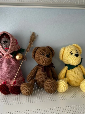 Handgjorda virkade nallar och docka - Styckpris: 250kr!  Dessa handgjorda virkade nallar och docka är perfekta för lek eller som dekoration. Nallarna är bruna och gula med rosetter, och dockan är klädd i rosa med en kvast. Pris kan diskuteras vid köp av fler.