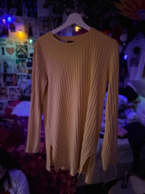 Gul ribbstickad klänning Gina Tricot - Säljer en långärmad, gul ribbstickad klänning från Gina Tricot. Tröjan har rund halsringning och slitsar i sidorna.