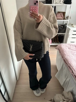Svart YSL axelväska i quiltat läder - Säljer en svart axelväska från Saint Laurent med klassiskt YSL-emblem i silver framtill. Väskan är quiltad i mjukt läder och har en kedjerem i silver som kan bäras både på axeln och crossbody. Perfekt storlek för det viktigaste och ger en lyxig touch till din outfit.