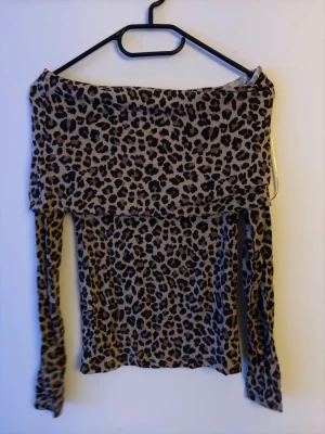 Offshoulder leopardmönstrad topp - Trendig offshoulder topp med leopardmönster i beige och svart. Toppen har långa ärmar och är tillverkad i ett mjukt, stretchigt material som sitter snyggt på kroppen. Perfekt för dig som vill sticka ut med en djurisk look. (Aldrig använd då jag inte vågat🙈)