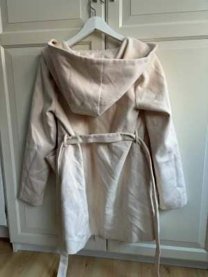 Ny beige kappa - Superfin kappa med knytband i midjan, fickor framtill och luva Aldrig använd, i nyskick