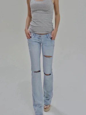 Ljusblå bootcut jeans med hål från G-rise - Nypris-890kr, Ljusblå bootcut jeans med slitningar över knäna. De är låga i midjan och helt nya endast testade. De är i storlek M med innerbenslängd 84cm.