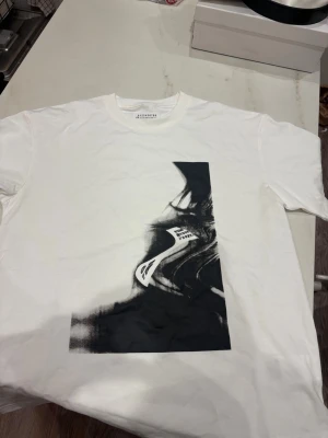 Vit t-shirt Maison Margiela print - Vit t-shirt från Maison Margiela med svart abstrakt print på framsidan. Klassisk rund halsringning och korta ärmar. Tillverkad i mjuk bomull för en skön känsla och stilren look.