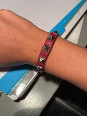 Valentino armband - Vinrött valentino armband, 100% äkta i använt skick och utan box.  Armbandet har slitage, är lite sönder på en kant (går att laga) och är böjt, men som inte påverkar hur det sitter på!