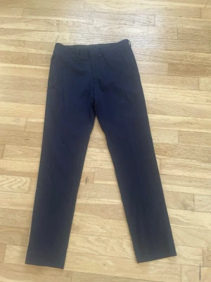 Mörkblå kostymbyxor Burton Menswear - Snygga mörkblå kostymbyxor från Burton Menswear London. Klassisk rak passform med midja på 76 cm. Perfekta för en stilren look och funkar till skjorta eller t-shirt. Tillverkade i ett mjukt och bekvämt tyg.