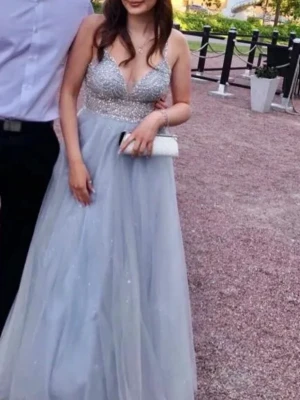 Ljusblå långklänning med paljetter - Säljer en superfin balklänning. Himmelsblå med silvriga detaljer och glitter. Perfekt för den som vill se ut och känna sig som en prinsessa på studentbalen!🩵. Använd en dag under min studentbal 2022, ej använd sedan dess och har bevarats väl upphängd i en ”klädpåse”. Köpt från Zalando! Fler bilder finns att få om man vill. För referens är jag 161cm lång och hade på mig ca 10cm klackar denna dag, dock enkel att korta ner hos skräddare ifall man behöver. Köpt för 2545, säljer för 800 eller bud✨