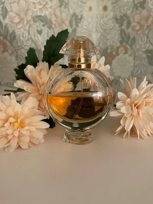 Olympea Eau de parfum - Köpt på kicks för 859 kr, använt halva parfymen.  En frisk amberdoft med en djärv kontrast mellan saltad vanilj och strålande blommor. Olympéa Eau de Parfum är doften av en modern gudinna som äger sin lust och alltid går efter det hon vill ha.